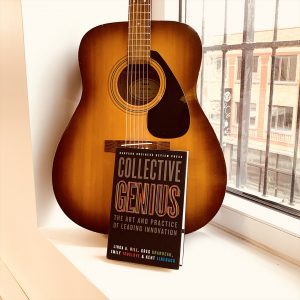 Le livre Collective Genius et une guitare
