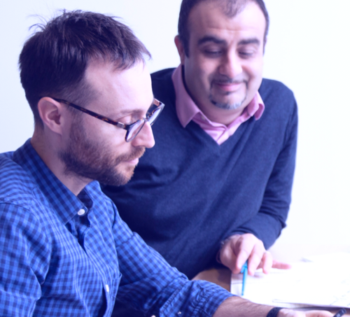 Photographie de deux hommes réfléchissant au dessus d'une feuille prise pendant un Design Sprint