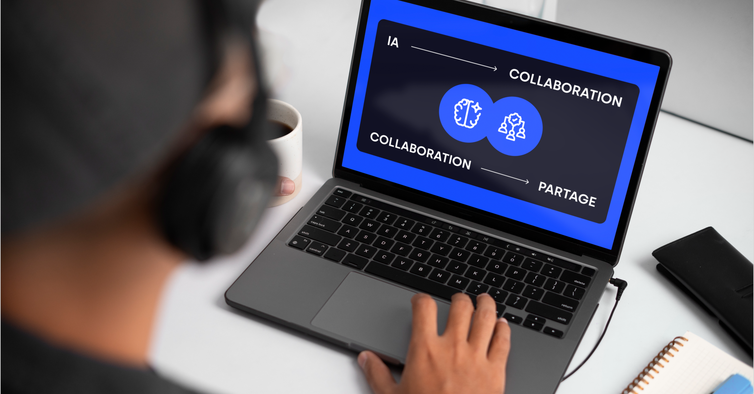 Personne travaillant sur un ordinateur portable affichant un écran bleu avec les mots «IA», «collaboration» et «partage», illustrant l’importance du travail collaboratif avec l’intelligence artificielle.